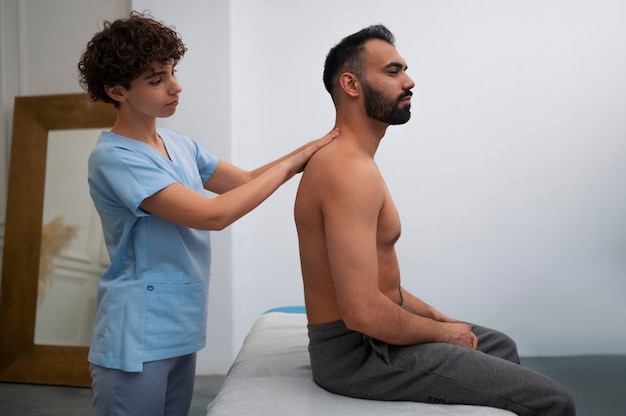 Terapeuta femenina en el centro de rehabilitación dando masaje de espalda