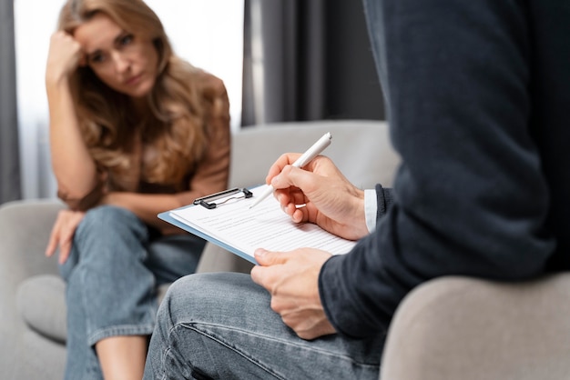 Terapeuta de hombre de tiro medio tomando notas cerca de la mujer