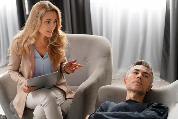 Terapeuta mujer hablando con el hombre tendido en el sofá