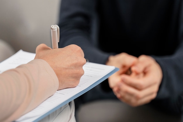 Terapeuta de mujer de tiro medio tomando notas en el portapapeles