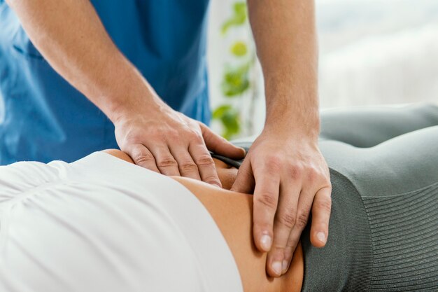 Terapeuta osteopático masculino comprobando el abdomen del paciente femenino