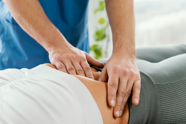 Terapeuta osteopático masculino comprobando el abdomen del paciente femenino