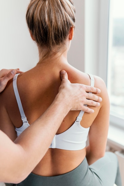 Terapeuta osteopático masculino comprobando la columna superior del paciente femenino