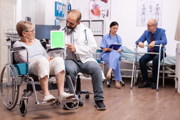 Terapeuta sosteniendo tablet pc con pantalla verde en el curso de la terapia