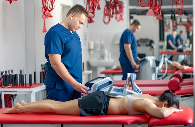 Foto gratuita la terapia electromagnética del médico fisioterapeuta de espalda utiliza equipos médicos