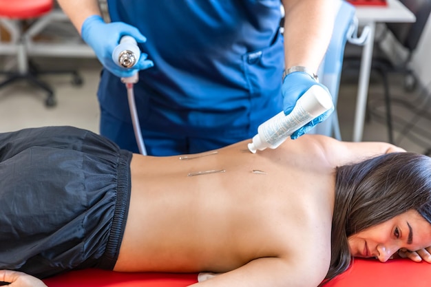 Foto gratuita terapia física con terapia de ondas de choque extracorpóreas para los músculos del cuello y la espalda.