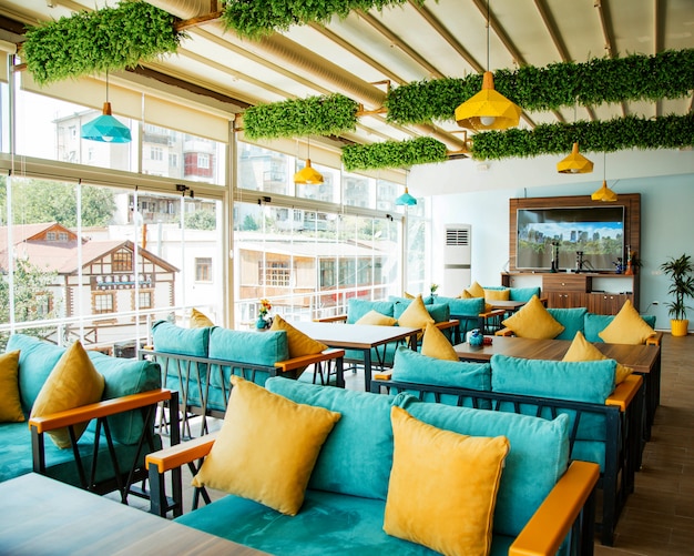 Foto gratuita terraza del café con sofás turquesas y almohadas amarillas