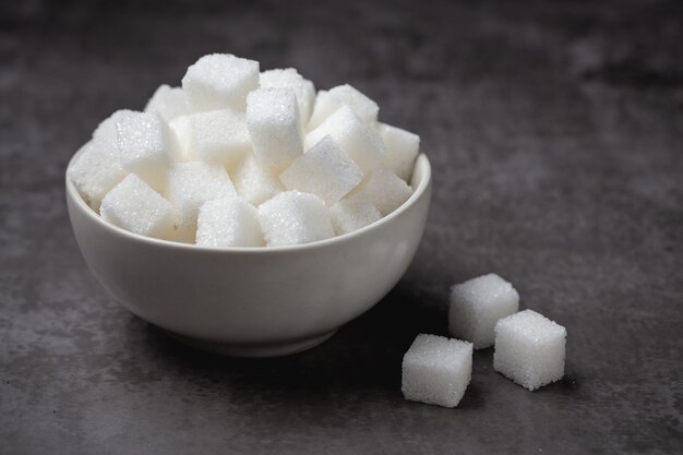 Terrones de azúcar blanco en un recipiente en la mesa.