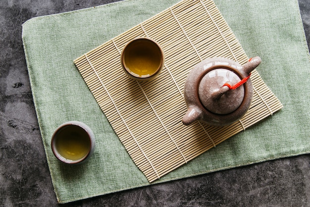 Tetera china tradicional y tazas de té en mantel sobre la servilleta