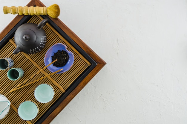 Foto gratuita tetera japonesa tradicional; cepillo; hierbas y tazas en bandeja de madera sobre fondo blanco