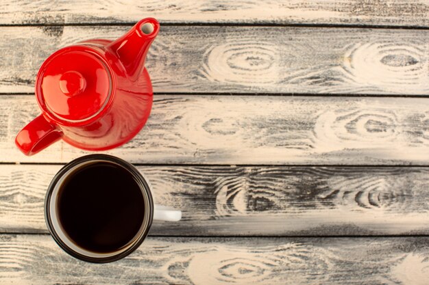 Una tetera roja de vista superior con una taza de café en el escritorio rústico gris beber color café