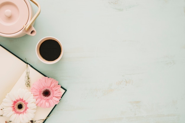 Tetera y taza cerca del cuaderno con flores