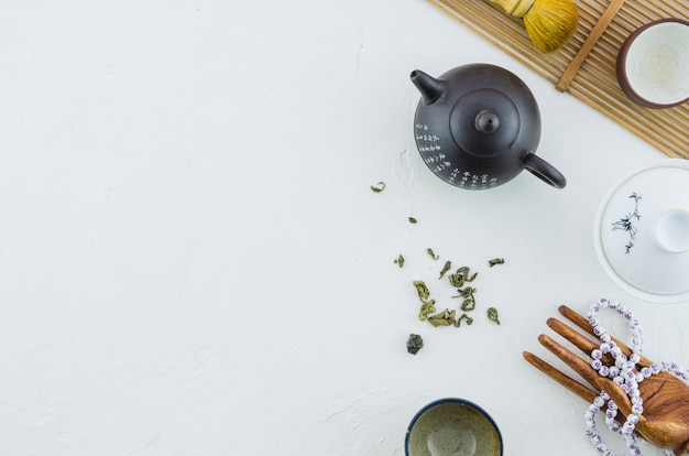 Tetera y tazas de cerámica del té con las hierbas aisladas en el contexto blanco