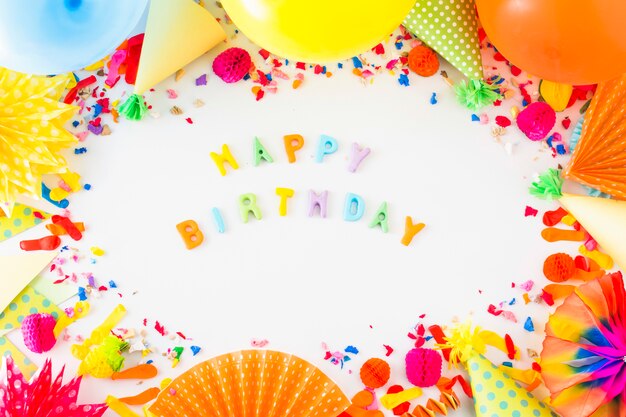 Texto colorido feliz cumpleaños rodeado de accesorios de fiesta en el fondo blanco