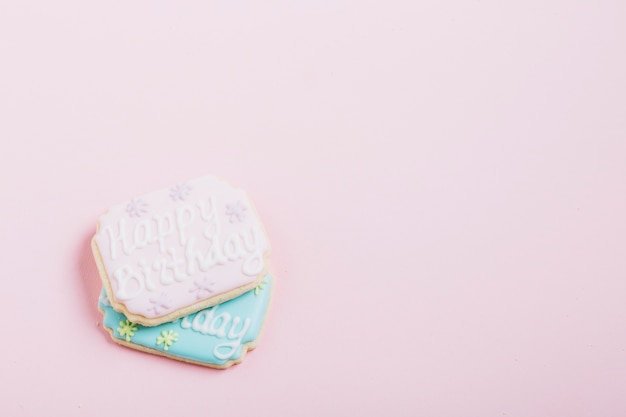 Foto gratuita texto de feliz cumpleaños en galletas frescas sobre fondo rosa