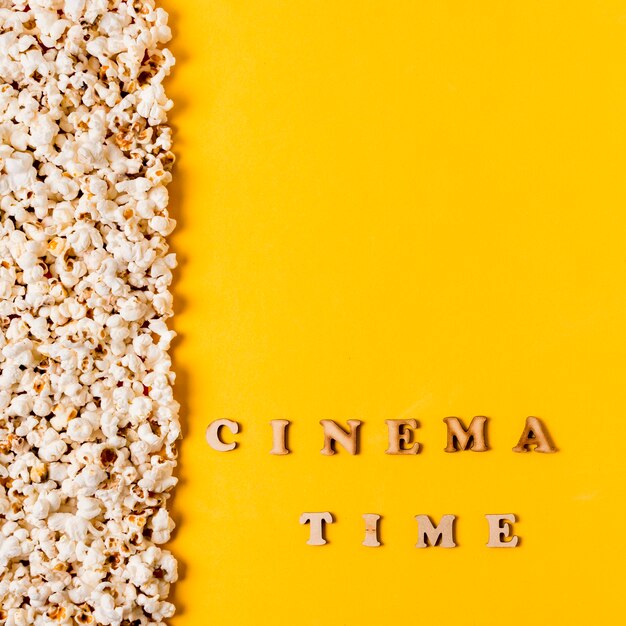 Texto de la hora del cine cerca de las palomitas de maíz sobre fondo amarillo