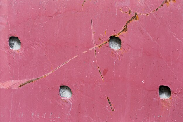 Textura de pared rosa dañada con agujeros