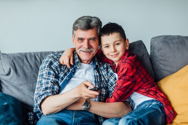 Tiempo familiar. Nieto alegre abrazando a su abuelo. Sala de estar.