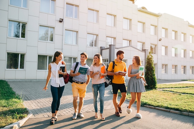 Tiempo libre de los estudiantes, ritmo de vida del campus de un bachillerato. Cinco estudiantes amigables están caminando