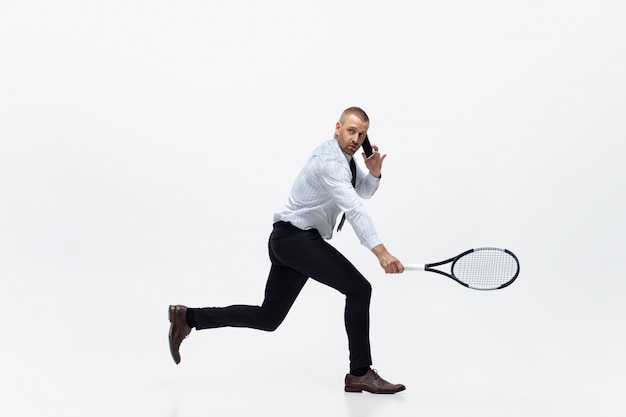 Tiempo de movimiento. Hombre en ropa de oficina juega tenis aislado en blanco. Empresario formación en movimiento, acción. Aspecto inusual para deportista, nueva actividad. Deporte, estilo de vida saludable.