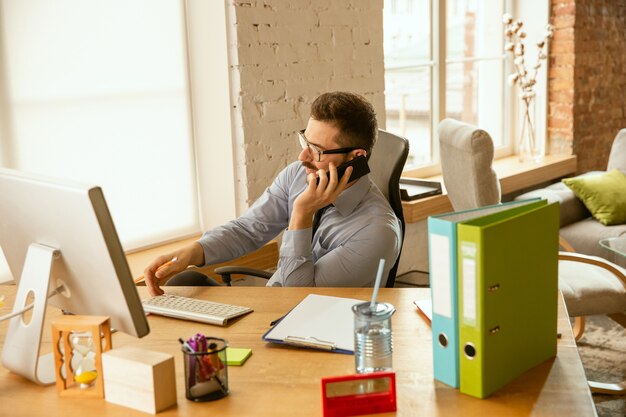 Tiempo de trabajo. Un joven empresario moviéndose en la oficina, consiguiendo un nuevo lugar de trabajo. Oficinista de sexo masculino joven mientras administra después de la promoción Se ve feliz