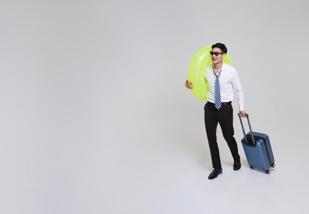 Tiempo de viaje de negocios hombre de negocios asiático con equipaje y nadar anillo inflable va a viajar