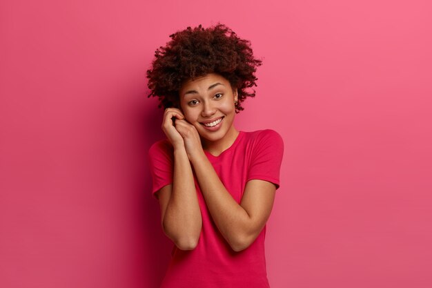 Tierna mujer de aspecto agradable mantiene las manos cerca de la cara