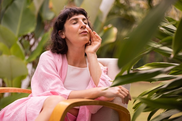 Tierna mujer caucásica joven morena en blusa rosa con los ojos cerrados se relaja sentado al aire libre Concepto de vacaciones de verano