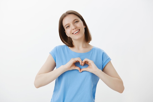 Tierna mujer linda que muestra el gesto del corazón, me gusta o ama algo