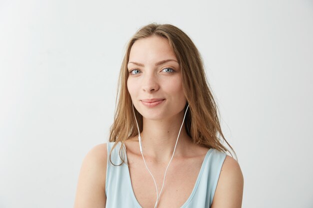 Tierna niña bonita soñadora escuchando música en auriculares.