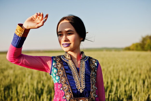 Tierna niña india en sari con maquillaje de labios violetas posó en el campo al atardecer