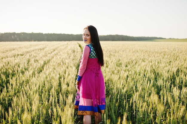 Tierna niña india en sari con maquillaje de labios violetas posó en el campo al atardecer