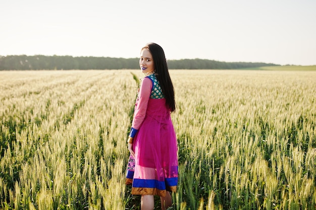 Tierna niña india en sari con maquillaje de labios violetas posó en el campo al atardecer