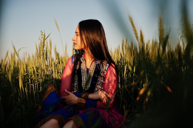 Tierna niña india en sari con maquillaje de labios violetas posó en el campo al atardecer