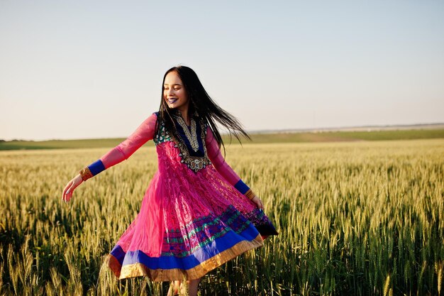 Tierna niña india en sari con maquillaje de labios violetas posó en el campo al atardecer