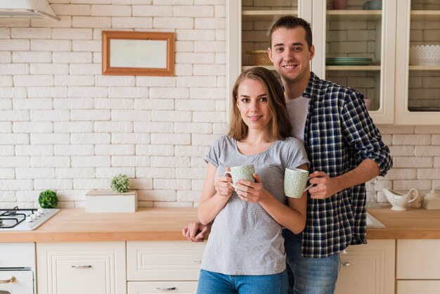 Tierna unión pareja bebiendo cerveza y de pie en la cocina