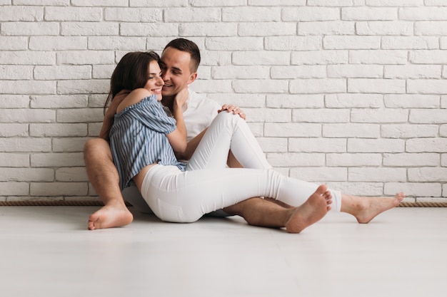 Tiernos abrazos y besos de hombre y mujer descansando en el piso.