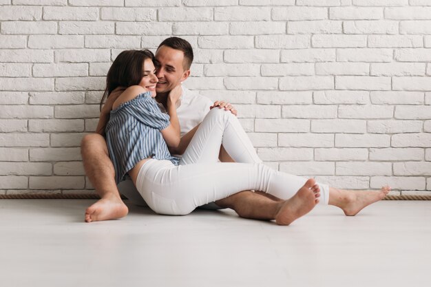 Tiernos abrazos y besos de hombre y mujer descansando en el piso.