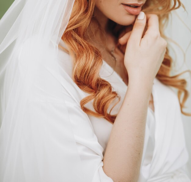 Tiernos labios y piel de encantadora novia con pelo rojo rizado.
