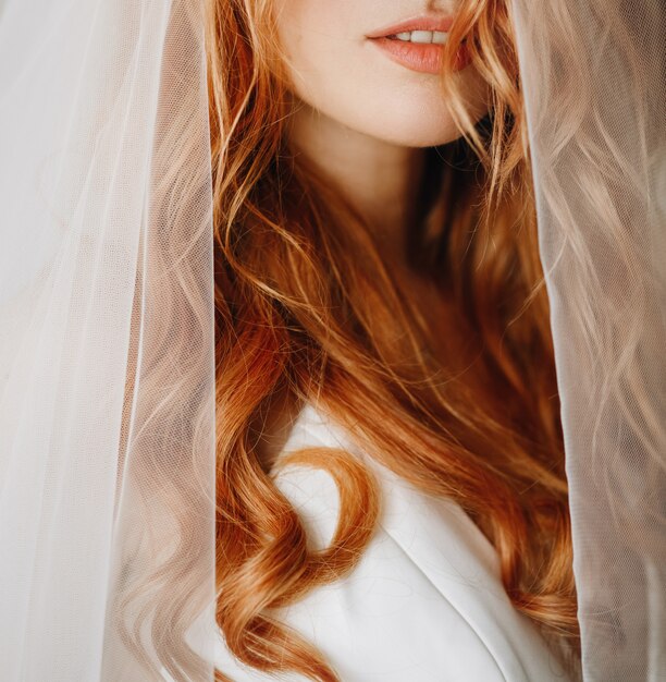 Tiernos labios y piel de encantadora novia con pelo rojo rizado.