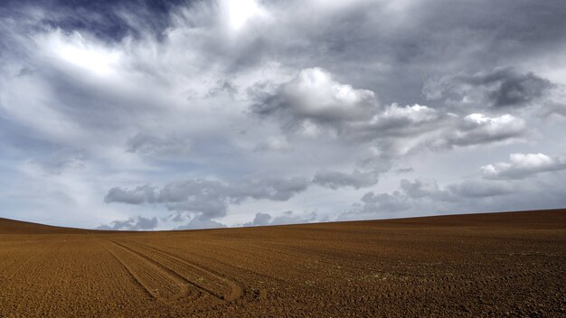 Tierra de arena marrón bajo el oscuro cielo gris nublado