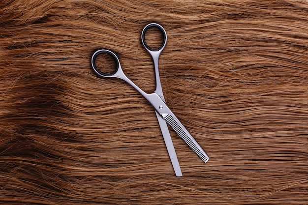 Foto gratuita tijeras de acero se encuentran en la ola de cabello castaño