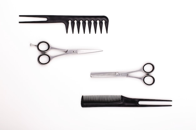 Las tijeras y los peines para el corte y el tratamiento del pelo mienten en una tabla blanca