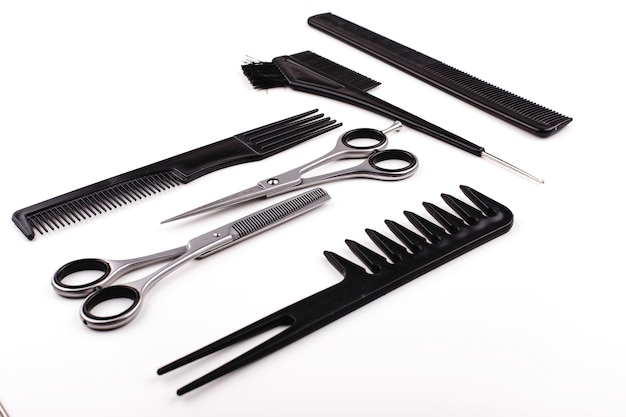 Las tijeras y los peines para el corte y el tratamiento del pelo mienten en una tabla blanca