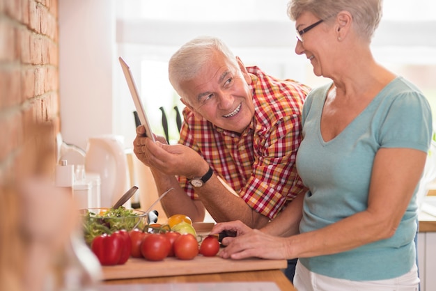 Útil hombre y su esposa preparando comida saludable