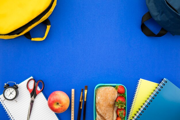 Útiles escolares y lonchera sobre fondo azul