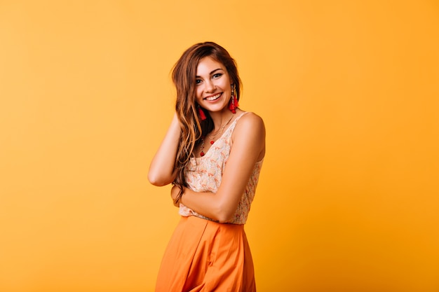 Foto gratuita tímida mujer europea en ropa amarilla posando en estudio con sonrisa sincera. espectacular modelo de mujer pelirroja que expresa felicidad.