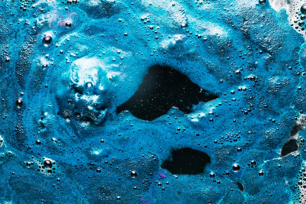 Tinte azul que se extiende en el agua sucia