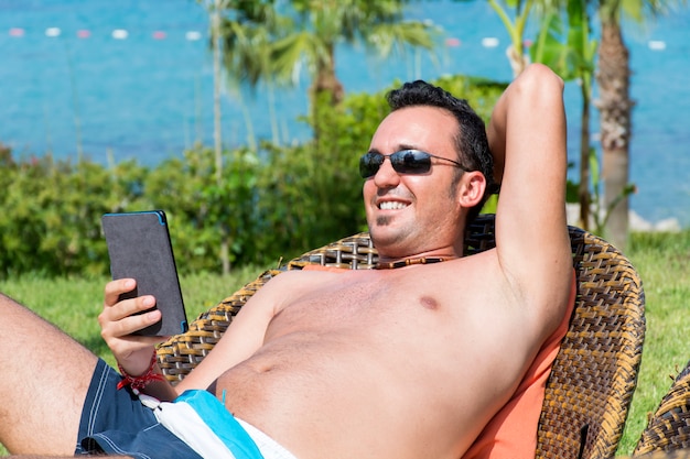 Tío alegre con su móvil descansando al aire libre