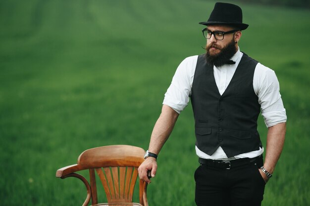 Tío elegante junto a una silla de madera